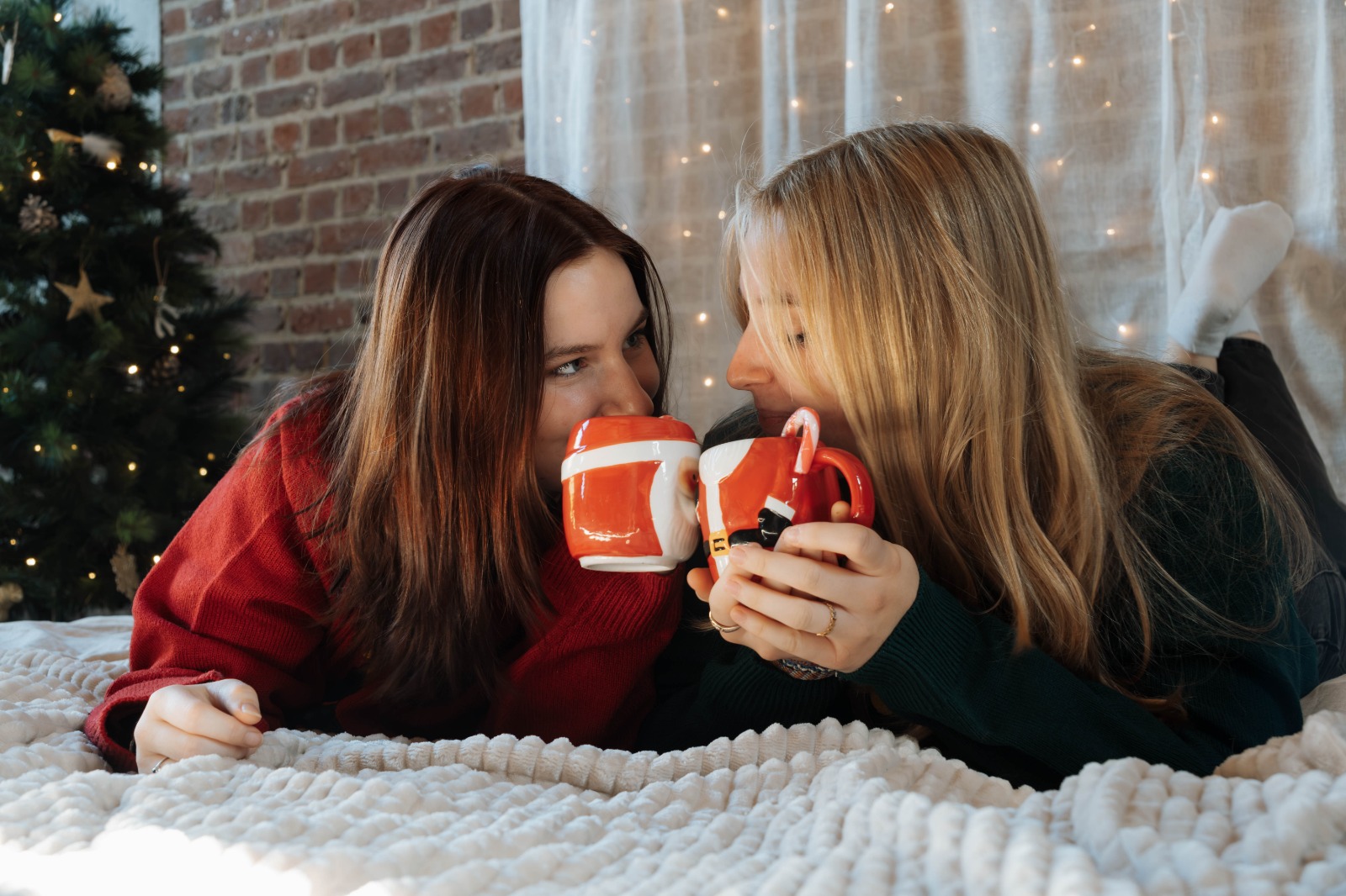 Twee vriendinnen met kerstmokken bij de kerstboom